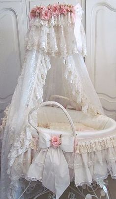 a white crib with pink flowers and lace on the top, sitting in front of a door