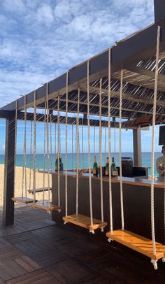 an outdoor bar on the beach with rope hanging from it's roof