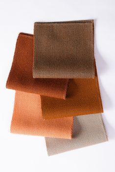 four different colors of fabric on a white surface with one orange and the other brown