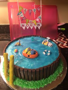 a birthday cake with an inflatable boat on the water and decorations around it