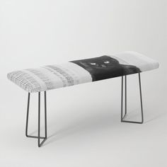 a bench with a black and white cat on it's seat cover sitting in front of a wall