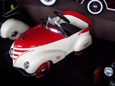 a red and white toy car sitting on top of a black floor next to other toys