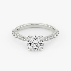 a white gold engagement ring with diamonds on the band and a round brilliant cut center stone