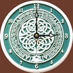 a green and white clock with celtic designs on it's face, against a brown background