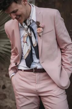 a man in a pink suit with a flower on his lapel, and tie