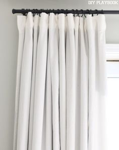 white curtains hanging on a black rod in front of a window with the words diy playbook written above it