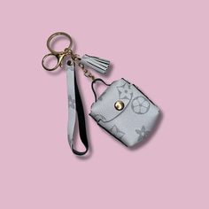 a small purse with a keychain hanging from it's side on a pink background