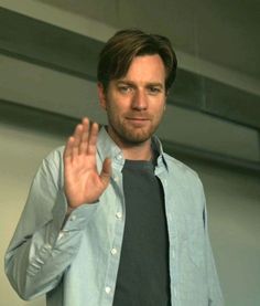 a man in a blue shirt and tie is making a hand gesture with his right hand