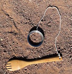 a wooden comb and ring on the ground next to a string that is hanging from it's end