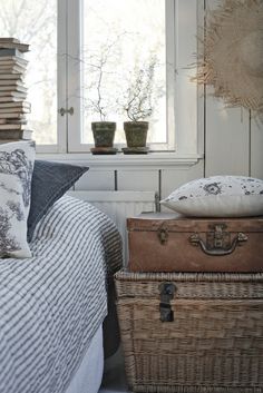 two suitcases stacked on top of each other in front of a bed with blue and white bedspread