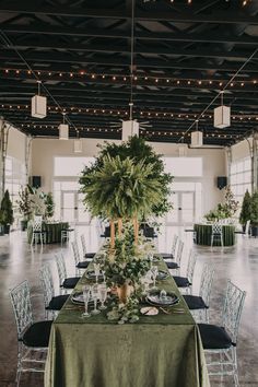 a long table is set up with green linens and greenery for an elegant wedding reception