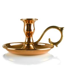 a brass plate with a candle holder on the side and a hook in the middle