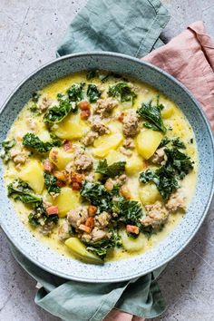 a bowl filled with meat, potatoes and spinach on top of a pink napkin