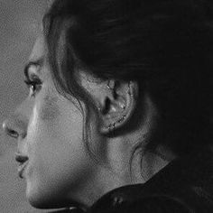 a black and white photo of a woman with ear piercings looking off into the distance