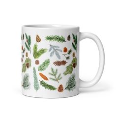 a white coffee mug with pine cones and leaves on it