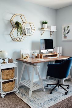 a desk with a computer on top of it in front of a wall mounted shelving unit