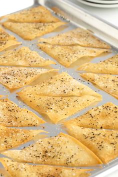 baked tortilla chips in a pan with seasoning sprinkled on top