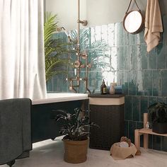 a bath room with a tub a sink and a mirror on the wall next to a potted plant