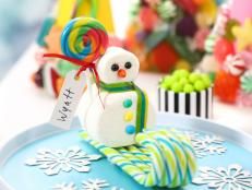 a small snowman sitting on top of a blue tray next to candy and candies