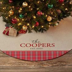 a christmas tree with presents under it on a wooden floor next to a sign that says the coopers est 2020