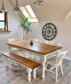 a dining room table with two benches and a clock on the wall above it in front of a window