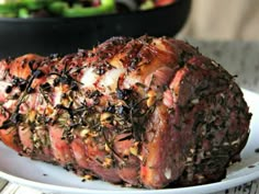 a piece of meat on a white plate with sprinkles and seasoning