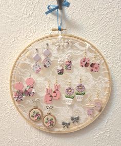 an embroidery hoop with earrings hanging from it's side on a wall next to a pair of scissors