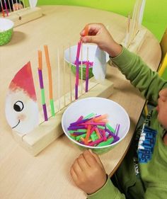 a little boy that is sitting at a table with some sticks in front of him