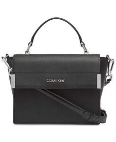 View More Calvin Klein Items   Calvin Klein Raelynn Saffiano Top Handle Flap Handbag Crossbody (Black/Silver) Poised, polished and ready to take on the day (or night), the Calvin Klein Raelynn Crossbody will remain a timeless classic for years to come. Mini sized bag; 6"W x 7"H x 3"D (width is measured across the bottom of handbag); 1 lbs. approx. weight Silhouette is based off 5'9" model 3-1/2"L handle; 23"L detachable strap Magnetic snap closure Silver-tone exterior hardware 1 interior zip poc Chic Top Handle Bag With Silver-tone Logo Plaque, Calvin Klein Black Formal Bag, Black Calvin Klein Bag For Formal Occasions, Modern Formal Calvin Klein Bag, Modern Calvin Klein Formal Bag, Formal Calvin Klein Leather Bag, Calvin Klein Formal Leather Bags, Black Bag With Silver-tone Logo For Everyday Use, Calvin Klein Leather Bags With Silver-tone Hardware