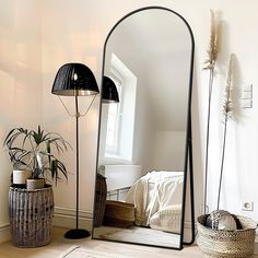 a large mirror sitting on top of a wooden floor next to a potted plant