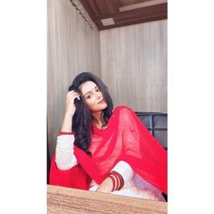 a woman sitting on top of a bed wearing a red shawl over her head