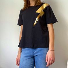 This Black T-Shirt With A Gold Lightning Bolt Across The Shoulder Is A Size Small As It Is A Lightweight, Conformable Shirt That Can Go Well With Many Bottoms. Lightning Bolt Outfit, Gold Lightning, Tops Black, Knitting Women, Lightning Bolt, Black T Shirt, Black Tshirt, Womens Tops, Tops & Tees