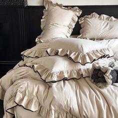 an unmade bed with ruffles and pillows on it in a bedroom setting