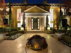 the front entrance of a house lit up at night with lights on and potted plants