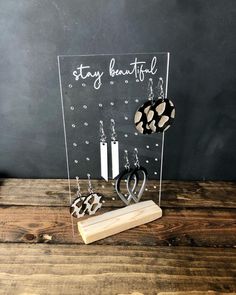 a clear acrylic stand with earrings and earring holders on it that says stay beautiful