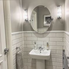 a white sink sitting under a bathroom mirror next to a radiator and towel rack