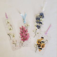 three tags with flowers on them sitting on top of a white table next to each other