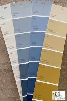 four shades of blue, yellow and white paint on the floor in front of a wall