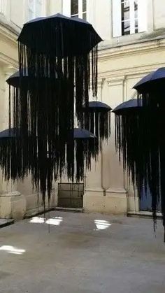 several black umbrellas hanging from the ceiling in an open area with concrete flooring