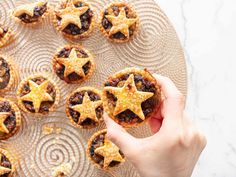 a person is holding up some cookies with stars on them in front of a platter