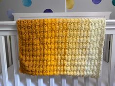 a crocheted blanket hanging from the side of a crib