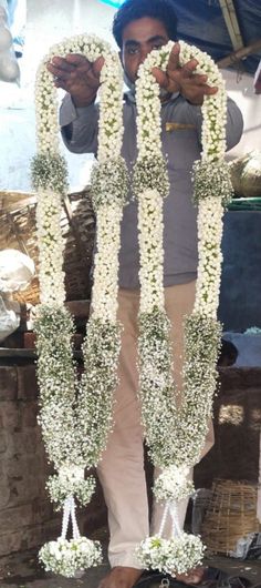 a man standing in front of a bunch of flowers with his hands up to the camera