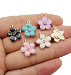 small flower charms in various colors and sizes on a person's palm holding out their hand