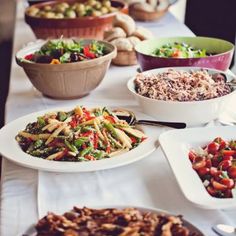 a long table filled with lots of different types of food on plates and serving utensils