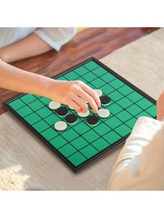 two people playing a game of checkers on the floor with one person's hand