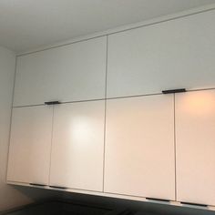 a kitchen with white cupboards and black counter tops in front of a wall light