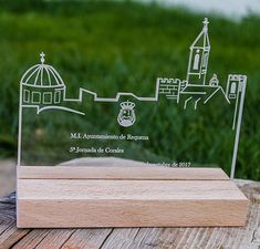 a clear acrylic plaque with a wooden base on a table in front of some grass