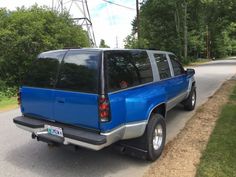 a blue pick up truck is parked on the side of the road