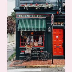 an old fashioned bicycle is parked in front of a british restaurant with red doors and green awnings