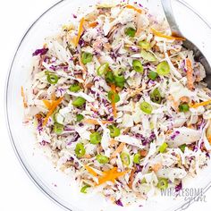 a bowl filled with coleslaw and carrots on top of a white table